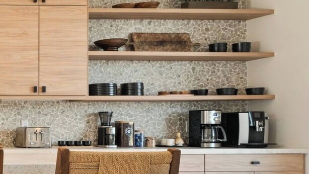 A kitchen with wooden cabinets, a stone backsplash, and various kitchen appliances.
