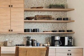 A kitchen with wooden cabinets, a stone backsplash, and various kitchen appliances.