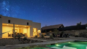 A modern house with a swimming pool, outdoor seating, and a starry night sky. - Stardust Luxe - Modern Desert Retreat - Heated Pool, Spa & Firepit (Yucca Valley)