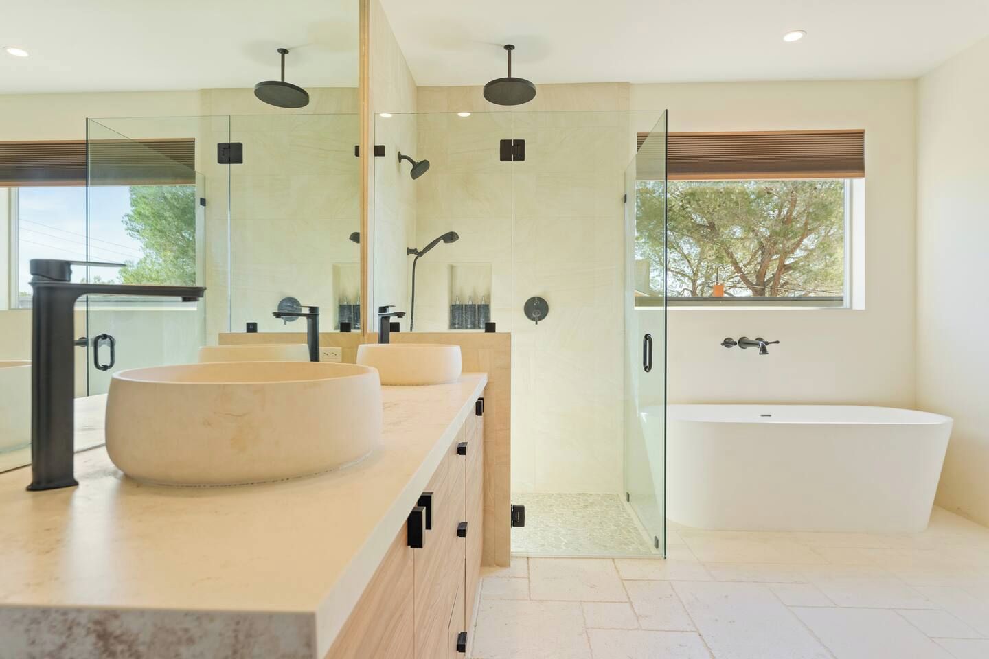 Uma casa de banho moderna com uma banheira grande, duas pias e zona de duche com divisória de vidro.