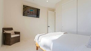 A bedroom with a bed, a chair, and a door.
