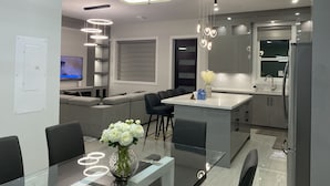 Ett modernt kök med en central köksö, inbyggda vitvaror och moderna belysningsarmaturer.