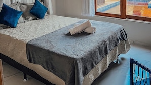 A bedroom with a bed, a window, and an air conditioning unit. - Chill House (Cruz)