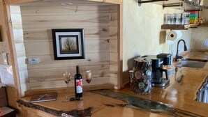 Una cocina rústica con encimera de madera, un cuadro enmarcado en la pared y una cafetera.