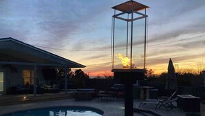 Una piscina con solárium, sillas de descanso y una pérgola con lámpara.