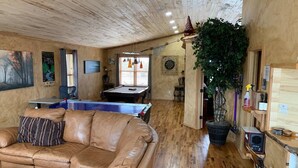 Una sala de estar acogedora con un sofá de cuero, una mesa de billar y una mesa de ping pong.
