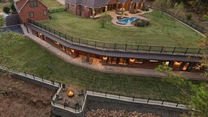 Una casa grande de varios pisos con piscina, mobiliario para exteriores y zona con brasero.