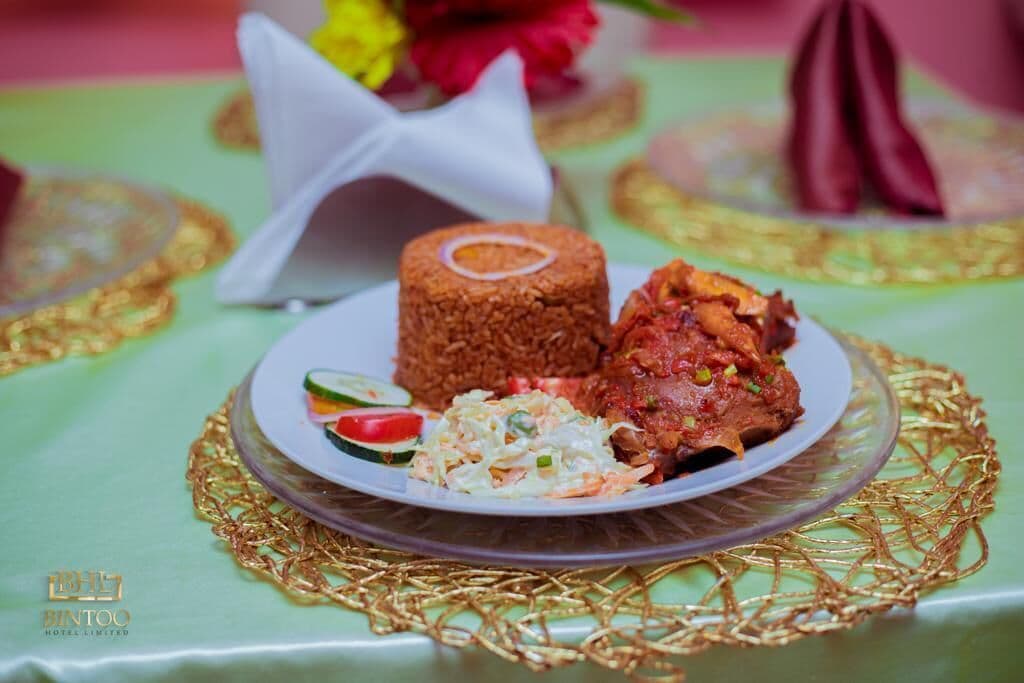A plate of food with rice, meat, and salad on a decorative plate with a gold pattern.