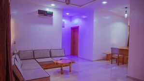 A modern living room with a sectional sofa, a wooden coffee table, and a dining area with a table and chairs. - BINTOO HOTEL LIMITED (Sagamu)