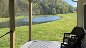 Eine überdachte Veranda mit Blick auf einen See und Wald.