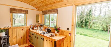A cozy kitchen with wooden cabinets, a bar counter, and a large window offering a view of the outdoors.