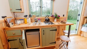 Una cocina compacta con armarios de madera, horno empotrado y ventana con vistas a un jardín.