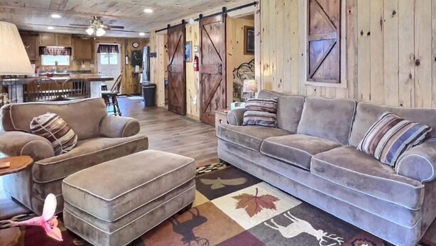 A rustic interior with a sofa, ottoman, and a patterned rug.