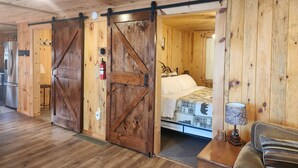 A rustic wooden room with a bed, a nightstand, and a sliding barn door.