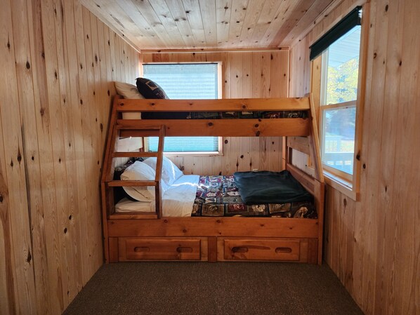 Habitación con literas, una escalera, un ventanal y un escritorio pequeño.