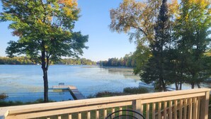A deck with a view of a lake, surrounded by trees.