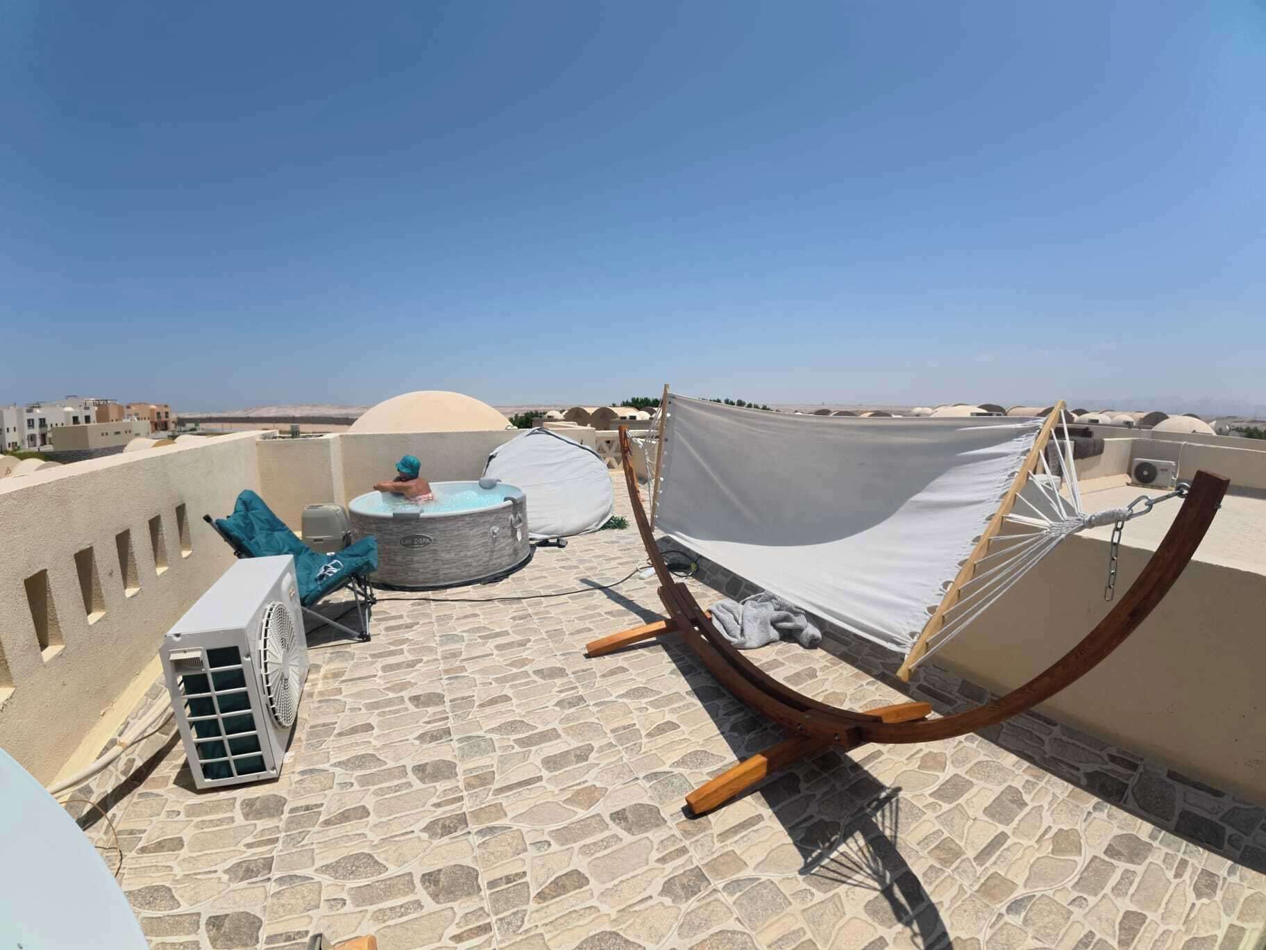 Een dakterras met een jacuzzi, een hangmat en een ventilator.