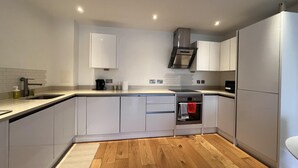 A modern kitchen with white cabinets, a built-in oven, and a wooden floor.