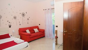 Une chambre à coucher avec un lit, un canapé rouge, une porte en bois et un mur décoré d’autocollants représentant des pissenlits.