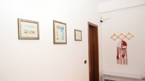 Un couloir avec des tableaux encadrés accrochés au mur, une porte en bois et un porte-chaussures rempli de chaussures.