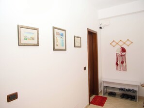 A hallway with framed pictures on the wall, a wooden door, and a shoe rack with shoes. - 2 Bed Apartment Sleeps 4 with Free Parking (Durres)