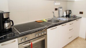 Une cuisine moderne avec une plaque de cuisson noire, des appareils en acier inoxydable et des meubles blancs.