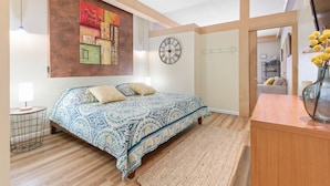 Une chambre à coucher comprenant un lit, une horloge, un tableau décoratif et une commode en bois.