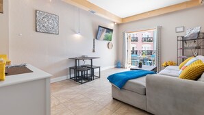 Un salon moderne avec un canapé, une petite table et un téléviseur fixé au mur.