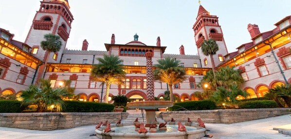 A historic building with a central fountain, arched walkways, and palm trees. - Cozy Stay with European Charm (Palm Coast)