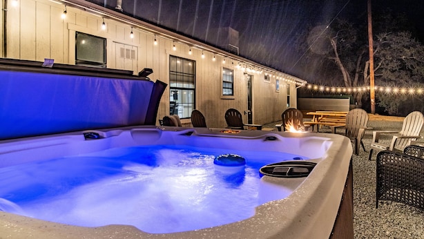 A hot tub with a blue light, surrounded by outdoor seating and string lights. - Fantastic Views w/ Hottub,  Firepit & Horseshoes (Ahwahnee)