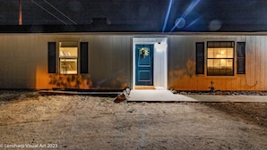 A single-story building with a blue door, a small porch, and a window with a light fixture. - Fantastic Views w/ Hottub,  Firepit & Horseshoes (Ahwahnee)