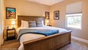 A bedroom with a wooden bed, two bedside tables with lamps, a ceiling fan, and framed pictures on the walls. - Fantastic Views w/ Hottub,  Firepit & Horseshoes (Ahwahnee)