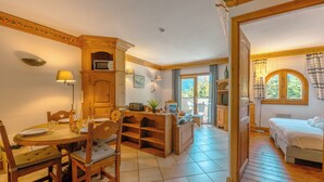 A room with a wooden dining table, chairs, a sofa, a bed, and a window with curtains. - Le Cristal MB6 View, Pool, Private Sauna, Parking & Free WiFi, Argentière (Chamonix), France (Argentière (Chamonix))