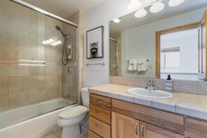 Ein modernes Badezimmer mit einer gläsernen Duschkabine, Toilette, Waschbecken und Holzschränken.