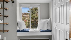 Ein Eckzimmer mit integriertem Sitzbänken, einem Fenster mit Blick auf eine Hügellandschaft und einer weißen Tür.
