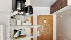 Una cocina con estanterías blancas, una cafetera y una puerta de madera.