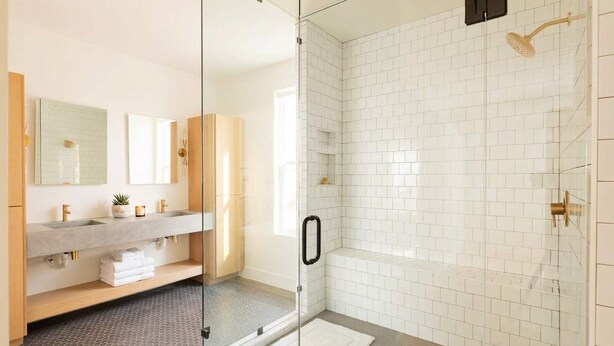 Ein modernes Badezimmer mit einer gläsernen Duschkabine, weißen Fliesenwänden und einem Holzwaschtisch mit Spiegel.