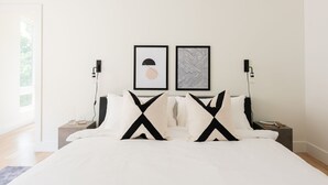 Ein modernes Schlafzimmer mit einem großen Bett, zwei Nachttischen und zwei Wandleuchten.