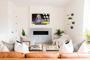 A modern living room with a flat-screen TV mounted on the wall, a fireplace, and a comfortable seating area with leather sofas and cushions. - Family-friendly Nashville home near Belmont, sleeps 10 with bunk room (Nashville)