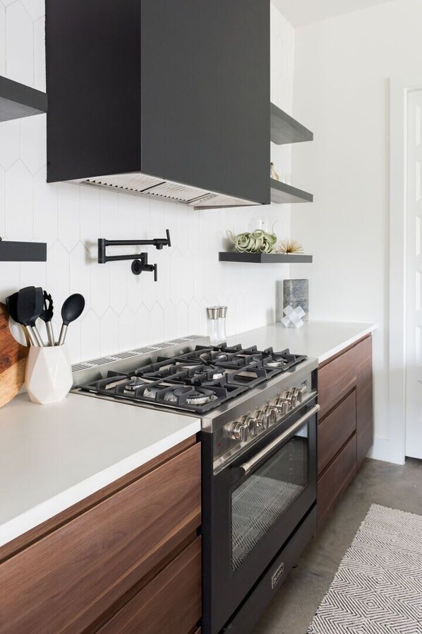 A modern kitchen with a gas stove, oven, and black cabinets.