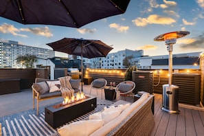 A rooftop patio with outdoor seating, a fire pit, and string lights. - Nashville rooftop fire pit home, sleeps 10 across 3 bedrooms (Nashville)