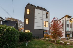 A modern two-story building with a flat roof, large windows, and a well-maintained garden with a tree and shrubs. - Nashville rooftop fire pit home, sleeps 10 across 3 bedrooms (Nashville)