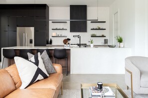 A modern kitchen with black cabinets, a white countertop, and a central island with bar stools.