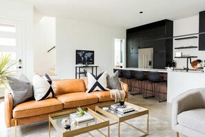 A modern living room with a sofa, coffee table, and a kitchen area with bar stools. - Downtown Nashville family home, sleeps 10, 3 bedrooms, gourmet kitchen (Nashville)