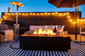 A fire pit with flames, a sofa with cushions, and string lights on a wooden deck. - Downtown Nashville family home, sleeps 10, 3 bedrooms, gourmet kitchen (Nashville)
