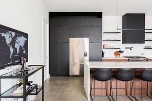 A modern kitchen with a stainless steel refrigerator, a bar area with stools, and a world map on the wall. - Downtown Nashville family home, sleeps 10, 3 bedrooms, gourmet kitchen (Nashville)