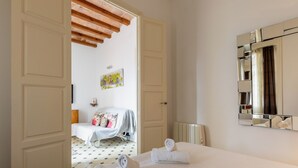 A hotel room with a bed, two towels, a mirror, and a door leading to another room.