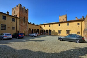 A courtyard with a historic building featuring a tower and arched walkways. - Certaldo - Certaldo 3 (Certaldo)