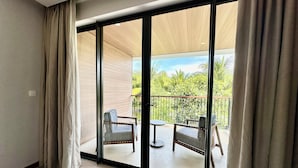A room with a sliding glass door leading to an outdoor balcony with two chairs and a small table. - Beach villa 3BR private swimming pool (Phu Quoc)