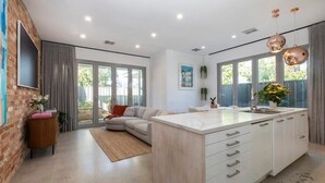 Een moderne keuken met een centraal eiland, grote ramen en een gezellige zithoek.